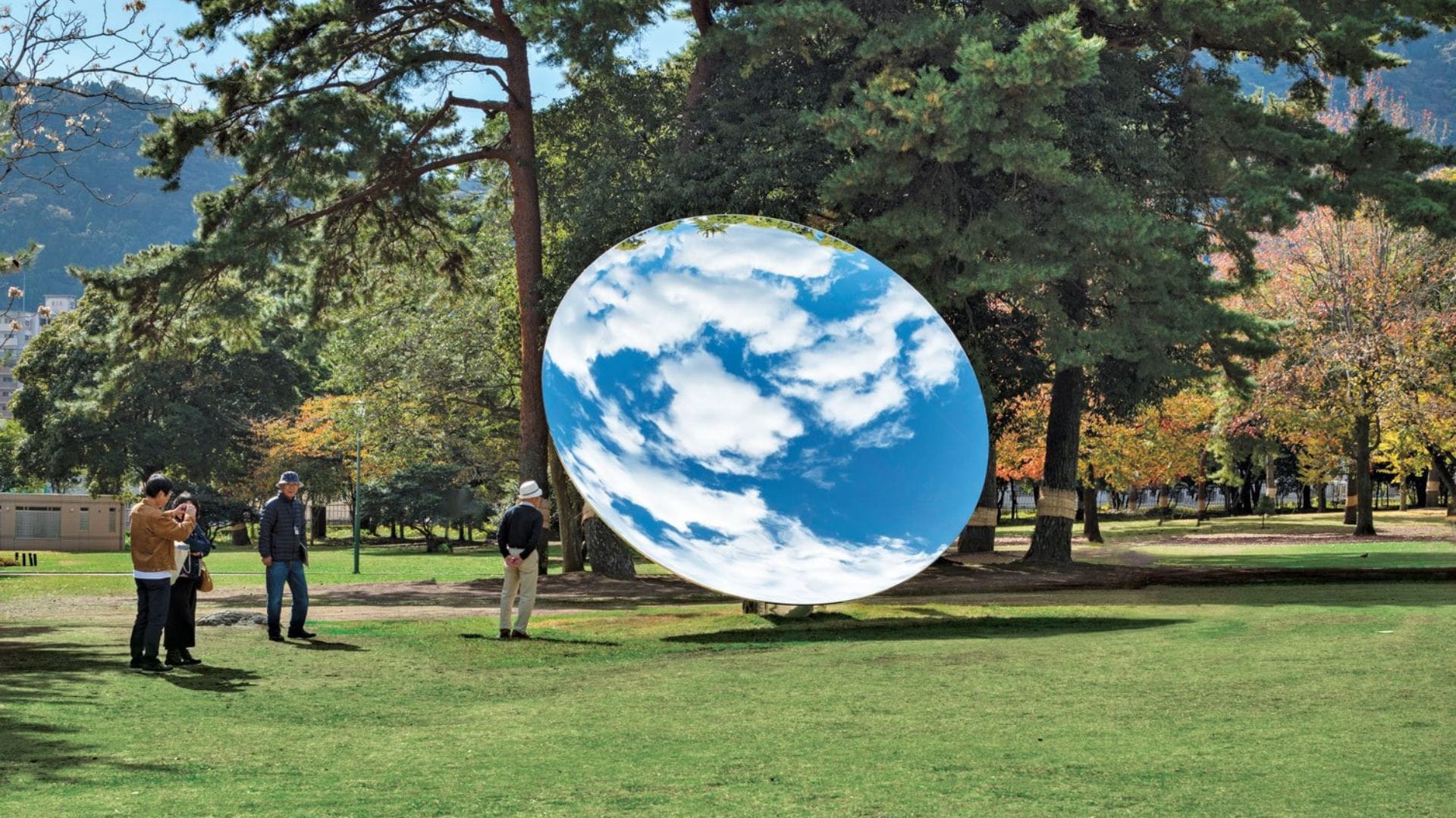 Uno specchio orientato verso il cielo riflette le nuvole al centro di un parco. Sky Mirror, installazione di Anish Kapoor.